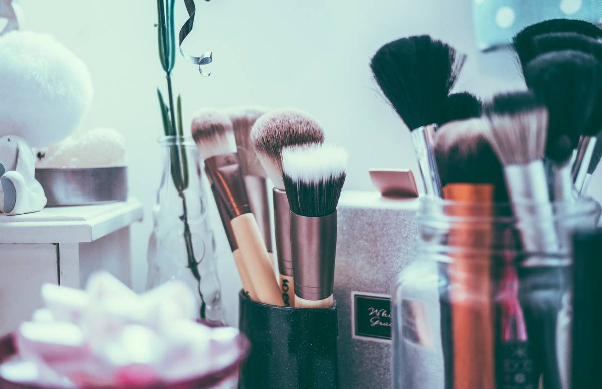 Side-by-side comparison: everyday makeup vs. stage makeup under identical stage lighting. Left face appears flat and washed out; right shows defined cheekbones, bold brows, and vivid lip color.