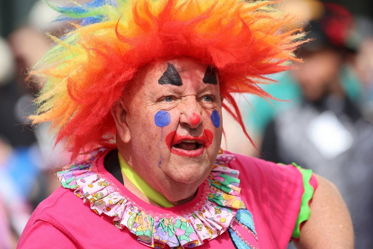 Close-up of detailed clown performance makeup with red nose, exaggerated eyes, and white base on a performer under stage lighting
